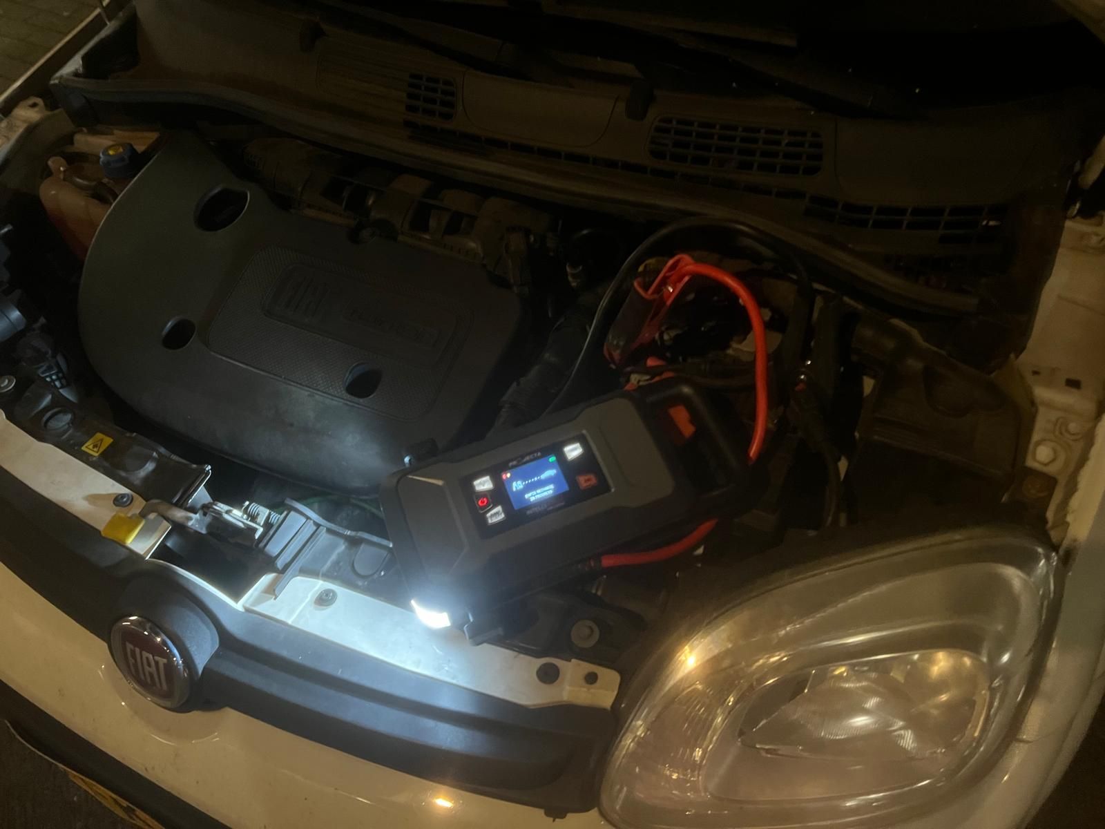 Starthulp met een jumpstarter bij een lege accu onder de motorkap, op locatie