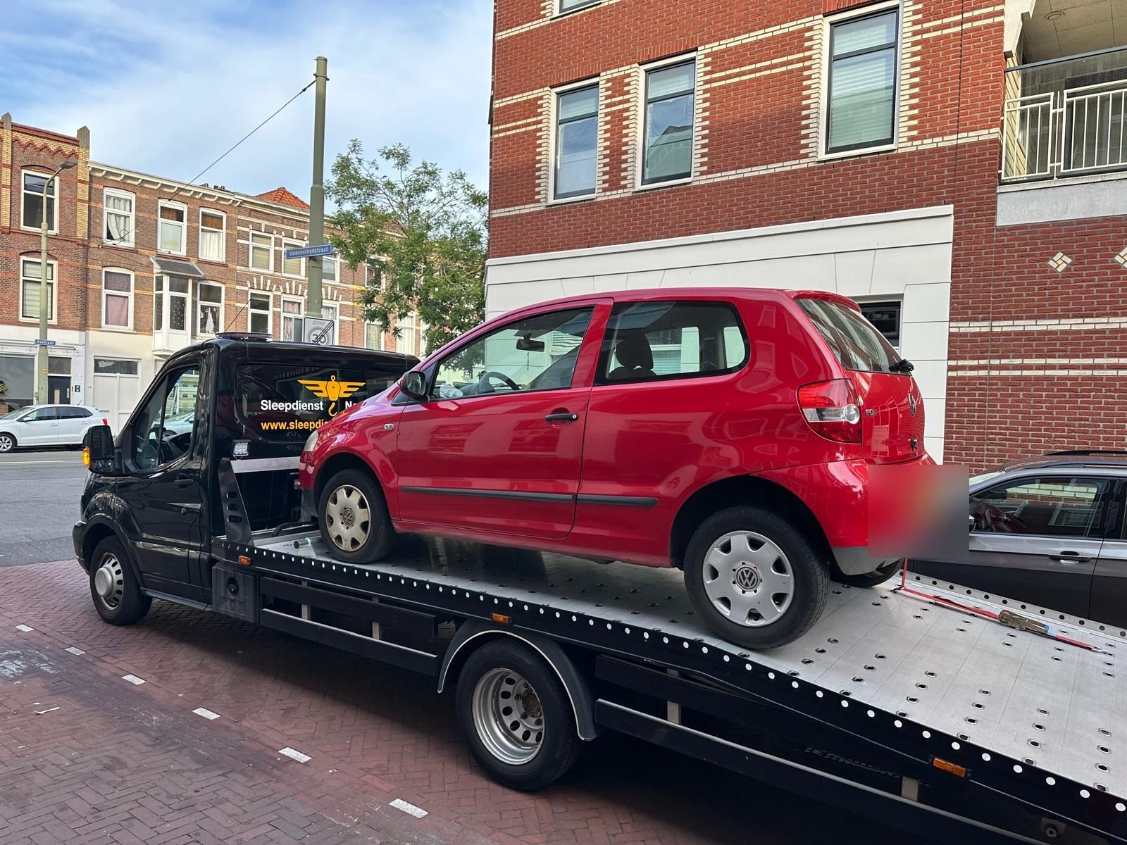 Rode Volkswagen Fox op de oprijwagen van Sleepdienst Nu in een stadsstraat