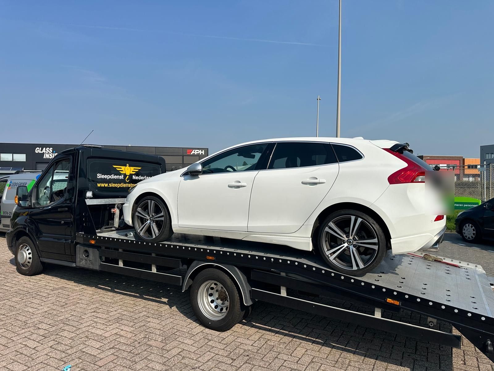 Witte Volvo op de oprijwagen tijdens autotransport over een bedrijventerrein