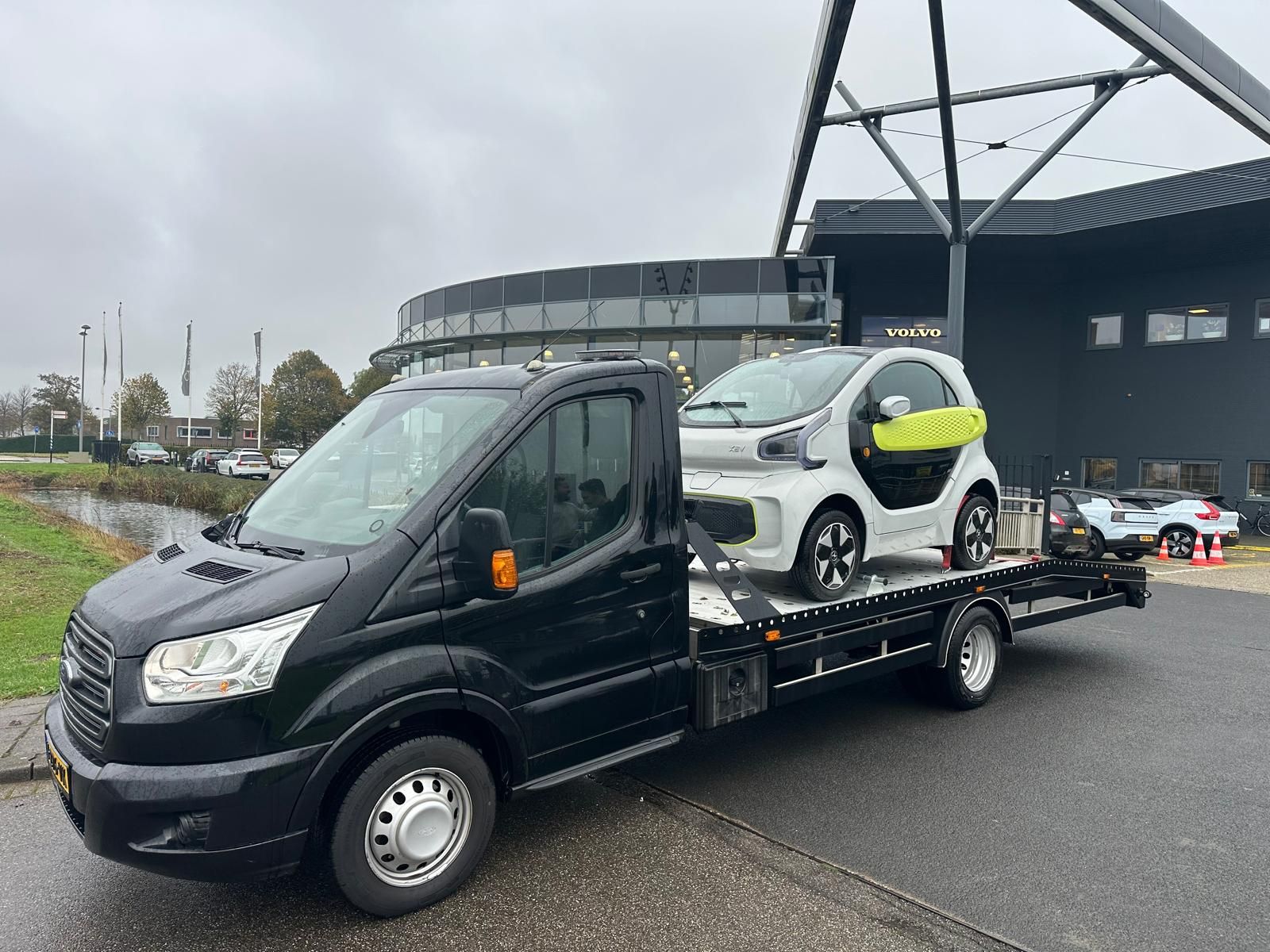 Kleine elektrische auto op de oprijwagen, vervoerd zonder dat de wielen draaien