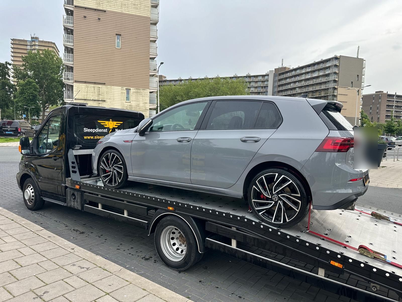 Autotransport: grijze Volkswagen Golf GTI vastgezet op de oprijwagen