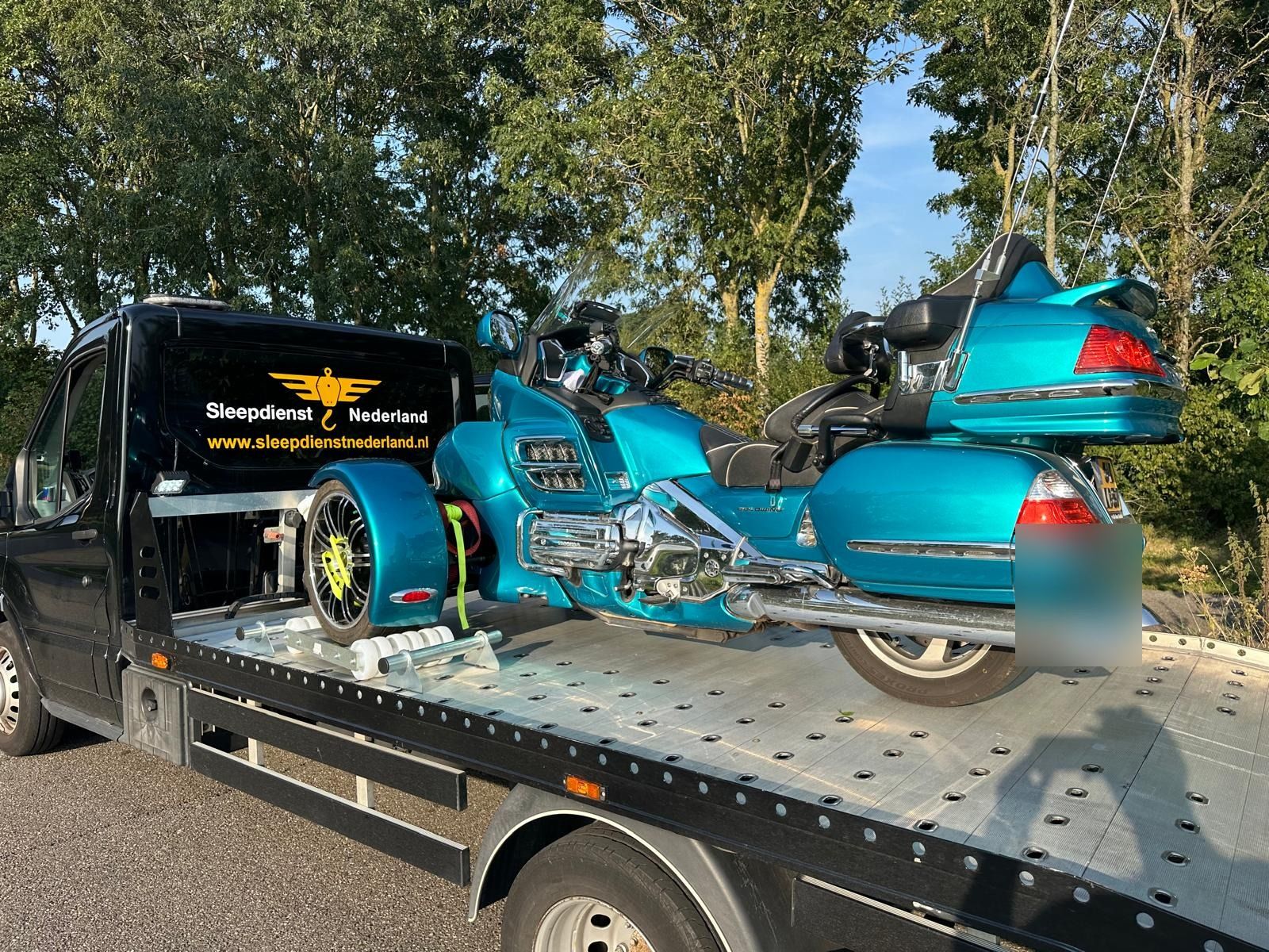 Motor pechhulp: turquoise Honda Gold Wing vastgezet op de oprijwagen