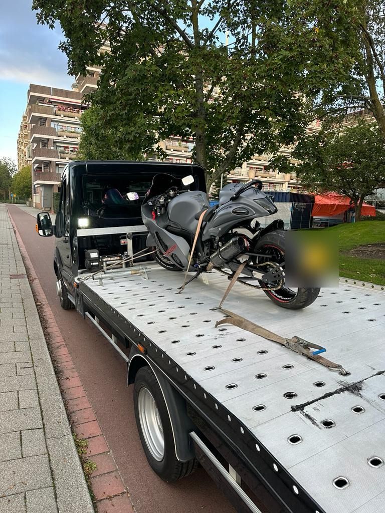Motortransport: motor met spanbanden vastgezet op de oprijwagen