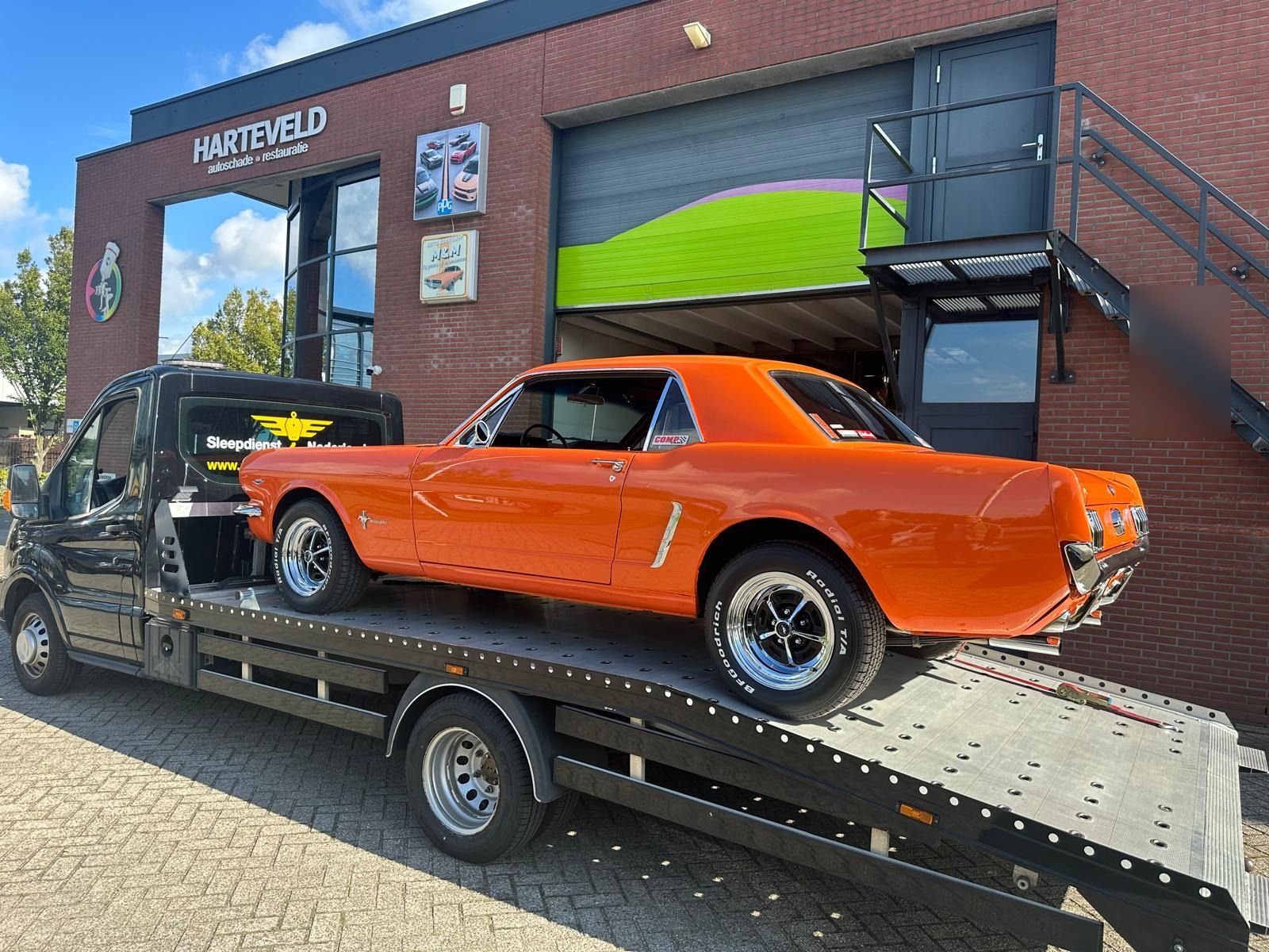 Oranje klassieke Ford Mustang veilig geladen voor oldtimertransport