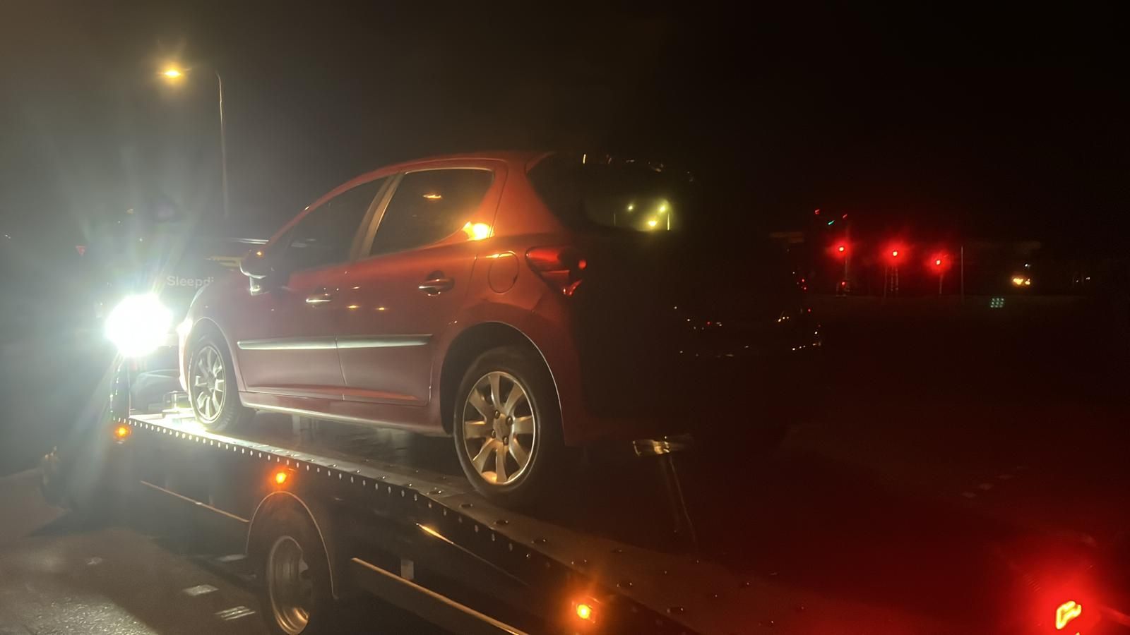 Autoberging in het donker: rode auto wordt met zwaailicht op de oprijwagen geladen