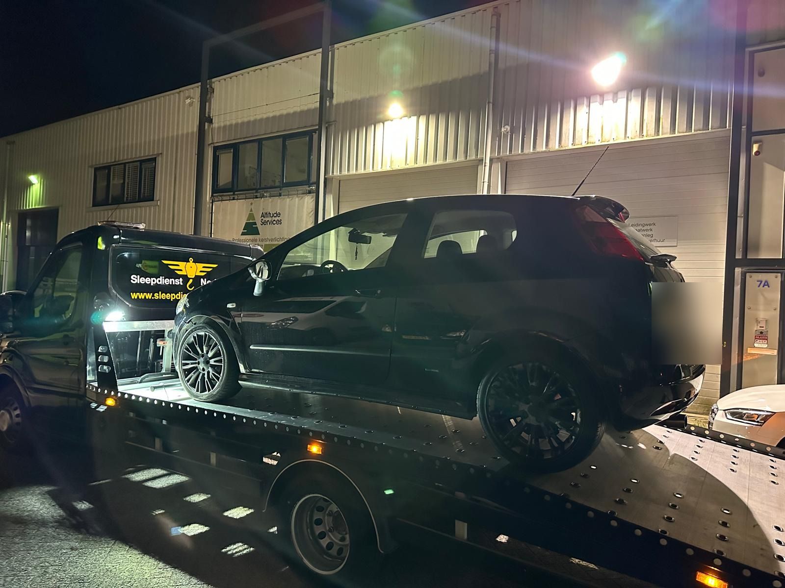 Pechhulp in de avond: zwarte hatchback wordt op de oprijwagen geladen