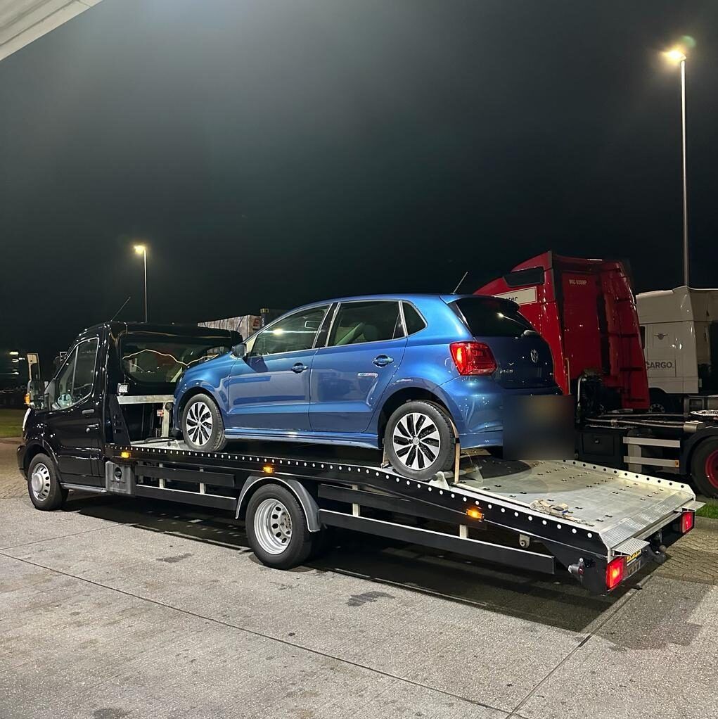 Blauwe Volkswagen Polo 's nachts op de oprijwagen van Sleepdienst Nu op een bedrijventerrein
