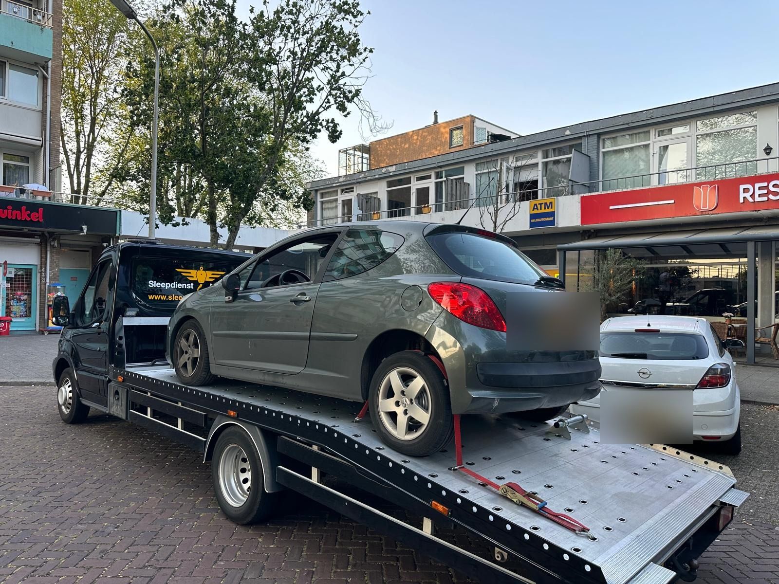 Sleepdienst in de stad: personenauto op de oprijwagen in een winkelstraat