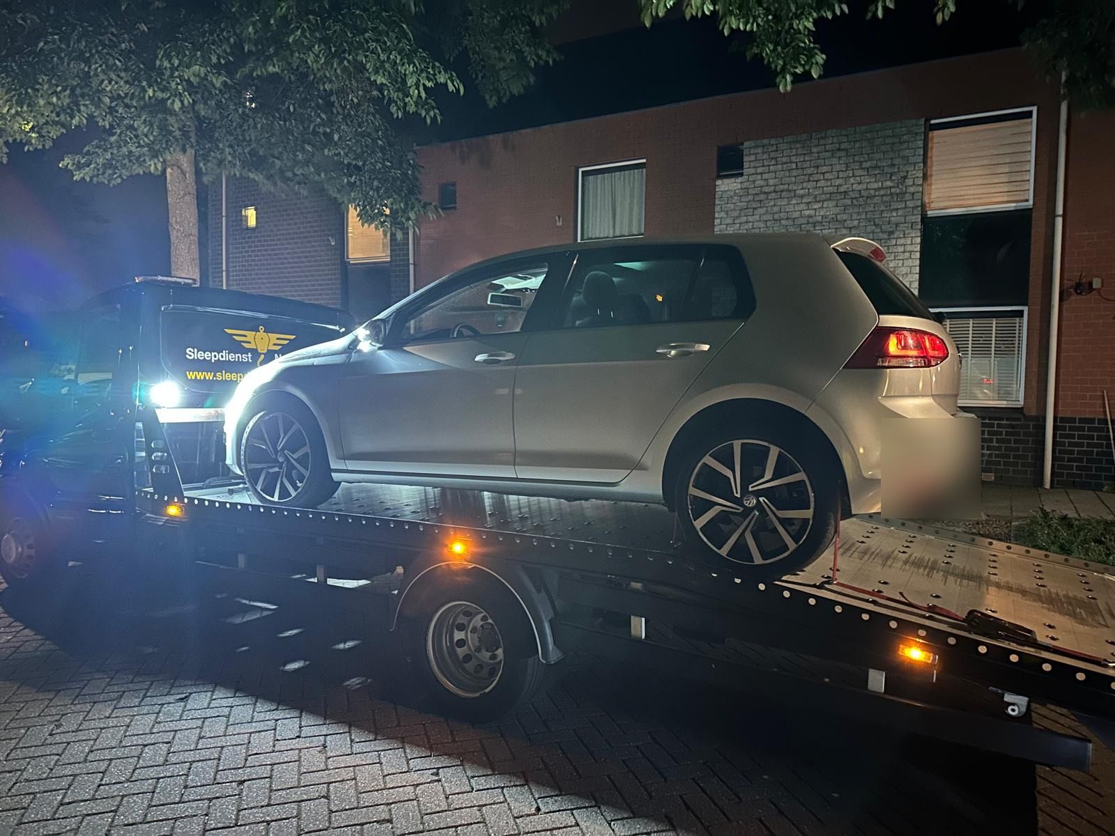 Zilveren Volkswagen Golf 's nachts op de oprijwagen in een woonwijk